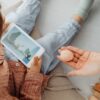 Young child engrossed in a smartphone video while holding a brain model indoors.