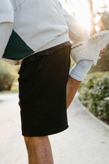 Close-up of a person stretching leg in a sunny outdoor park, ideal for fitness themes.