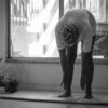 A person in Brazil stretching indoors during a rainy day in black and white.
