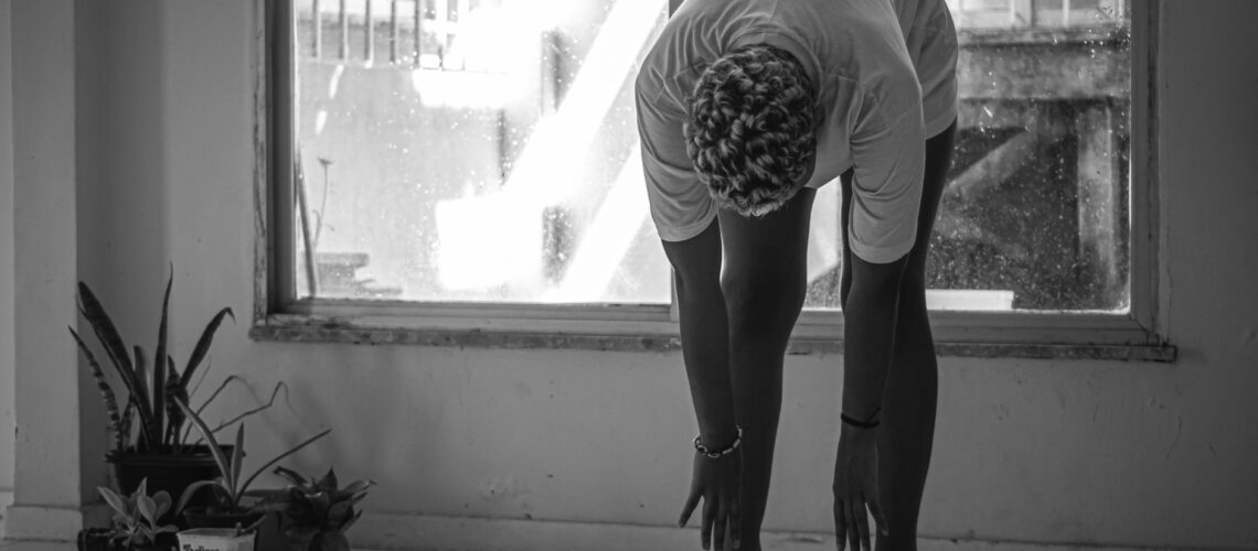 A person in Brazil stretching indoors during a rainy day in black and white.