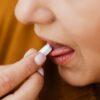 Close-up image of a woman taking a pill, emphasizing health and medication.