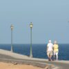 Senior couple walking on a seaside promenade enjoying a peaceful day by the ocean.