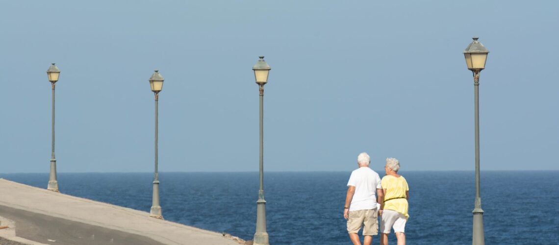 Senior couple walking on a seaside promenade enjoying a peaceful day by the ocean.