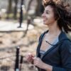 Side view of young African American female smiling while running in park against blurred background