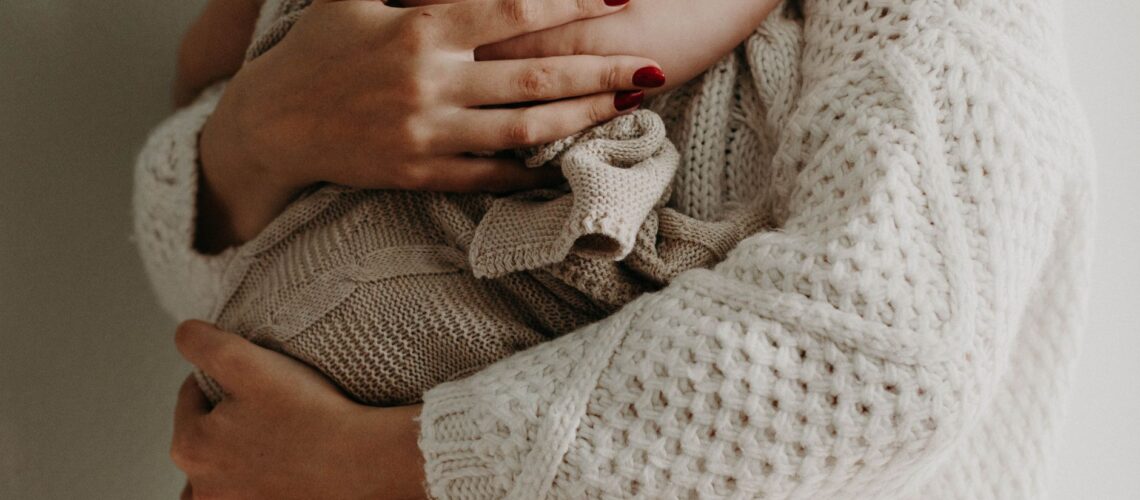 Close-up of a mother holding her baby in warm knitwear, conveying love and togetherness.