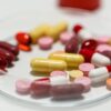Assorted colorful pills and capsules arranged on a Petri dish for pharmaceutical analysis.