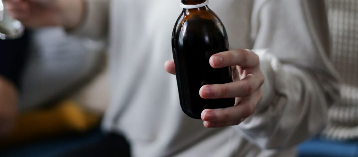 Close view of a person holding an amber medicine bottle, signifying health care and treatment.