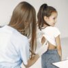 A female doctor uses a stethoscope to examine a child in a medical examination room.