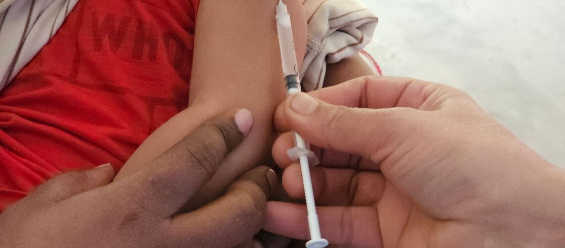 A child getting a vaccination shot administered by a healthcare professional indoors.