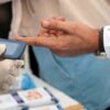 A healthcare professional checks blood glucose at a public event.