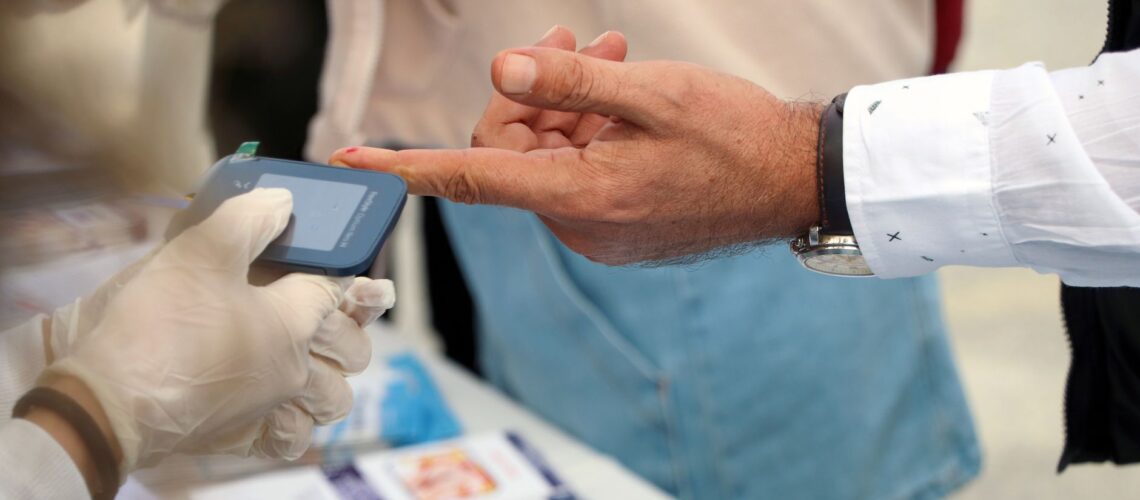 A healthcare professional checks blood glucose at a public event.