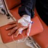 Close-up of a patient's hand receiving chemotherapy treatment in a medical facility.