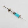 Close-up of a vintage glass syringe filled with blue liquid on a white background, minimal healthcare concept.