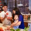 Parents and baby enjoying quality time in the kitchen with fresh vegetables.