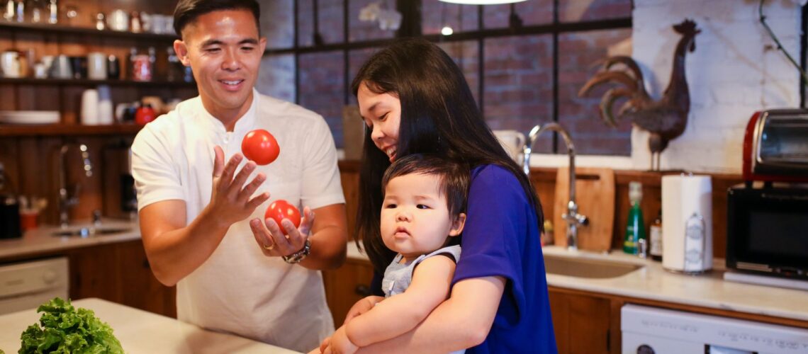 Parents and baby enjoying quality time in the kitchen with fresh vegetables.