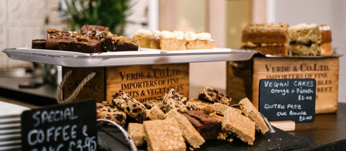 Assortment of vegan and gluten-free cakes on display at a cafe. Perfect for indulgence.