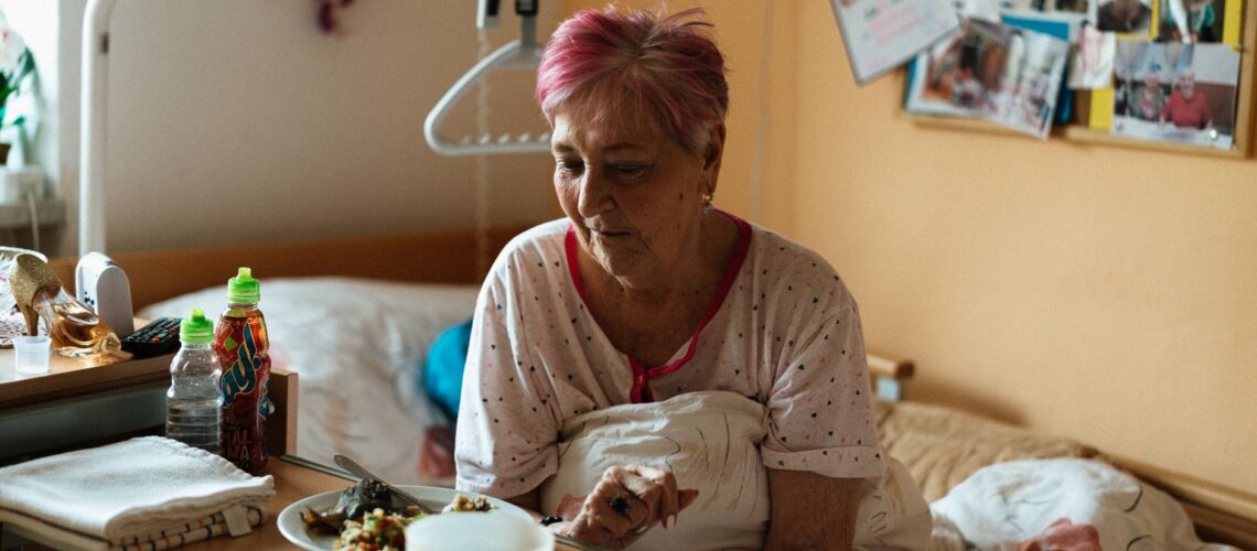 Elderly woman enjoying a meal in a cozy retirement home setting.