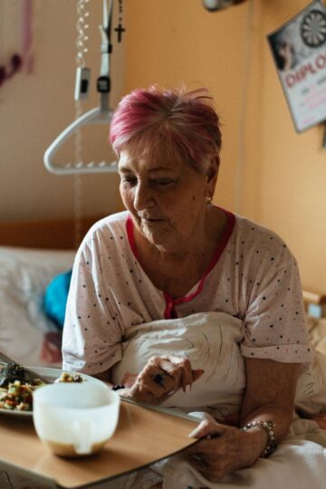 Elderly woman enjoying a meal in a cozy retirement home setting.
