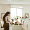 Pregnant woman slicing vegetables in a bright kitchen setting, embracing healthy lifestyle.