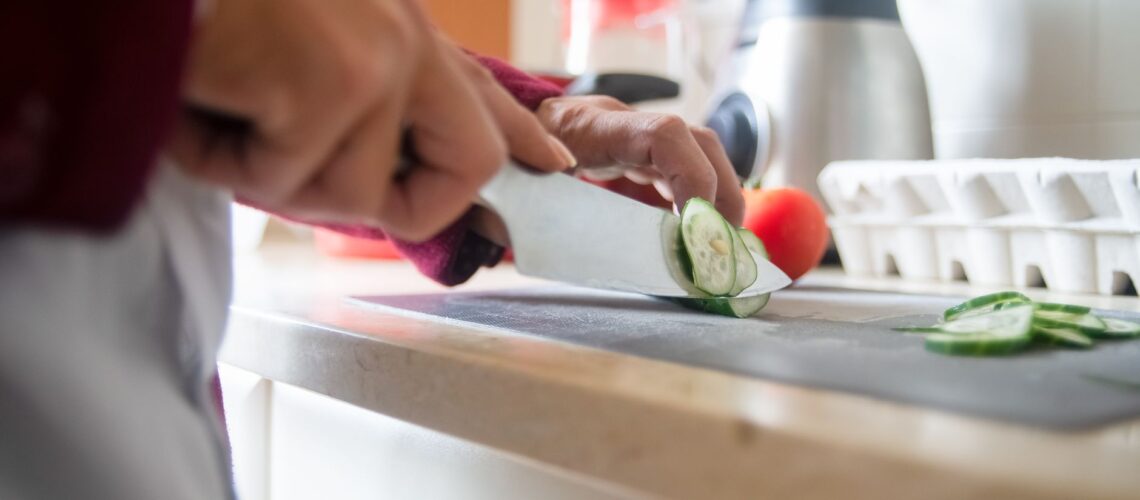 Close-up of a person slicing cucumbers on a kitchen counter for a healthy meal prep.