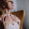 A mature woman gently massaging moisturizer into her neck, highlighting skincare routine and self-care.