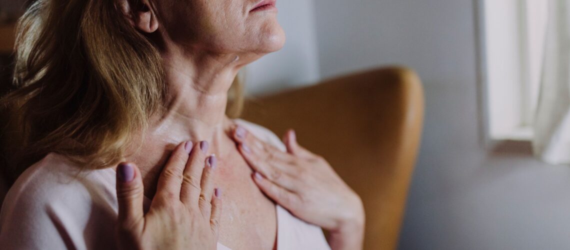 A mature woman gently massaging moisturizer into her neck, highlighting skincare routine and self-care.