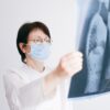 Doctor analyzes lung x-ray wearing a mask in a clinical setting.