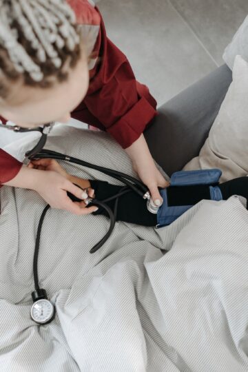 Paramedic measuring patient's blood pressure indoors, illustrating home healthcare assistance.
