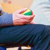 Elderly man holding a colorful therapy ball indoors, promoting relaxation and health.