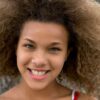 A smiling teenager with beautiful natural curls enjoying the day outdoors, embodying vibrant youthfulness.