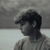 Side profile black and white portrait of a teenage boy outdoors, exuding a serene mood.