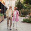 Happy senior couple walking together in a lush outdoor urban setting.