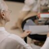 An elderly woman examines papers from the comfort of her living room.