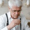 Elderly man analyzing scent from a test tube, focused on fragrance.
