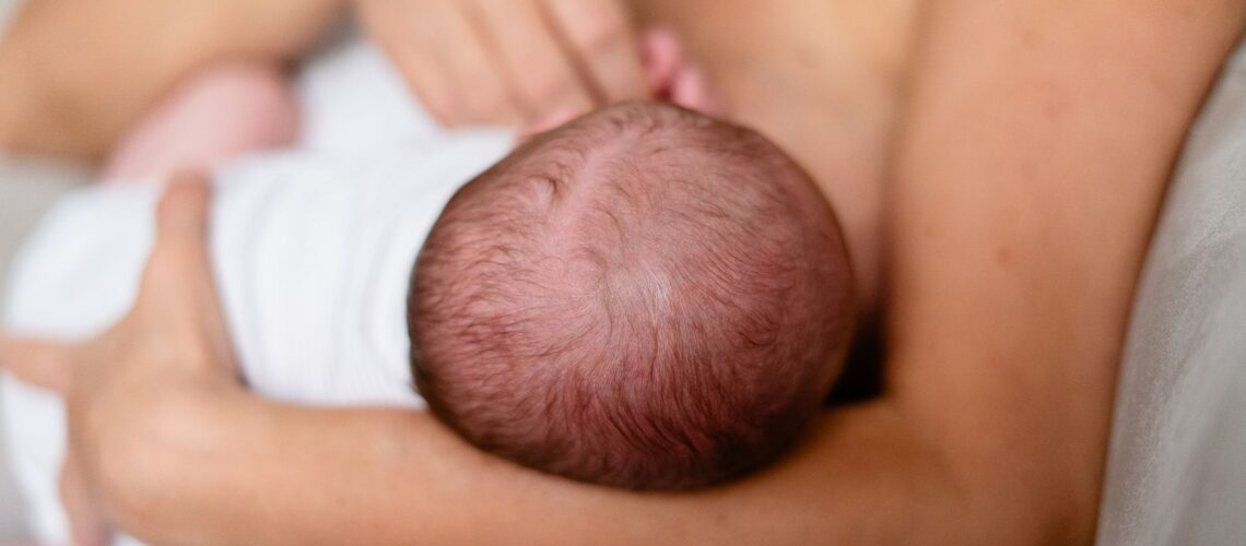 Tender moment of a mother breastfeeding her newborn, highlighting love and bonding.