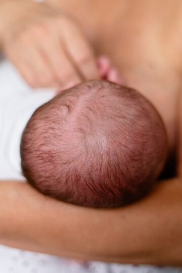 Tender moment of a mother breastfeeding her newborn, highlighting love and bonding.
