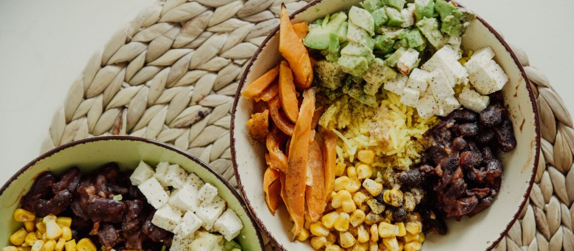Top view of vegetarian bowls with avocado, corn, beans, and cheese for a delicious meal.