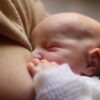 A newborn baby peacefully breastfeeding, capturing an intimate moment of mother-child bonding.
