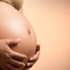 A tender close-up of a pregnant woman's hands holding her belly, symbolizing maternity and love.