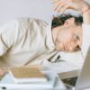 A tired Caucasian man at a desk, showing signs of exhaustion and stress, exemplifying workplace burnout.