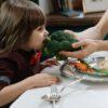 Cute child eating broccoli, promoting healthy eating habits indoors.
