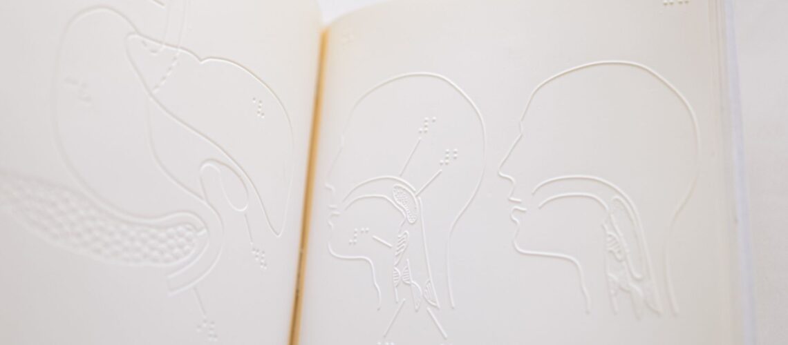Detailed close-up of embossed anatomy diagrams on an open braille book page.