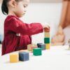 A young girl engaging with colorful wooden blocks, fostering creativity and learning in a playroom.