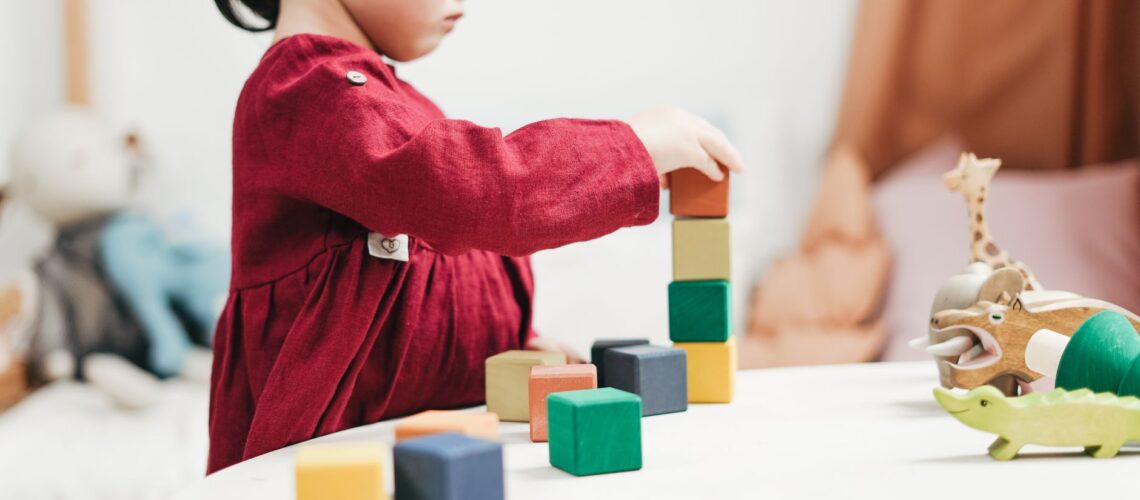 A young girl engaging with colorful wooden blocks, fostering creativity and learning in a playroom.