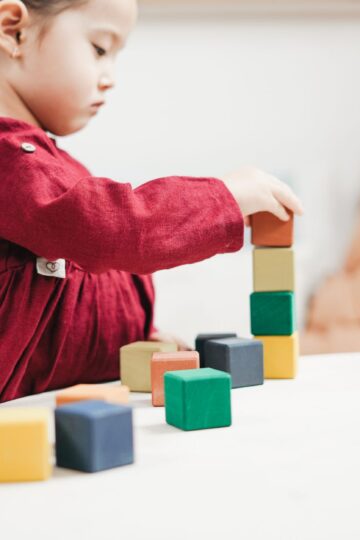 A young girl engaging with colorful wooden blocks, fostering creativity and learning in a playroom.