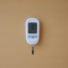 Close-up of a digital glucose meter displaying blood sugar level on a brown surface.