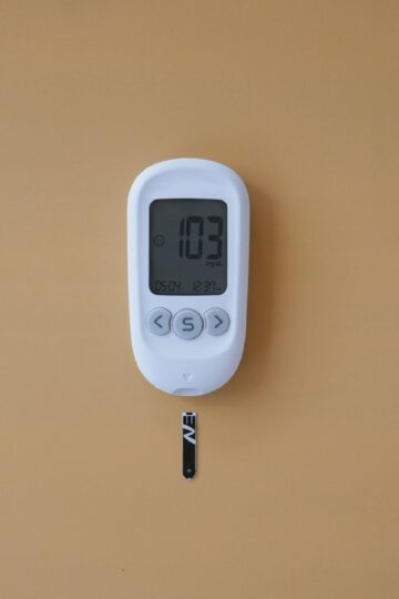 Close-up of a digital glucose meter displaying blood sugar level on a brown surface.