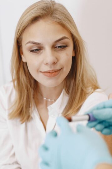 Blond woman in clinic receiving blood test with healthcare professional holding sample.
