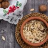 Close-up of pumpkin seeds in a terracotta bowl with walnuts on a rustic wooden surface. Perfect for food photography.