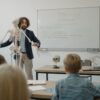 Teacher explaining human skeleton to students in a biology class with models.